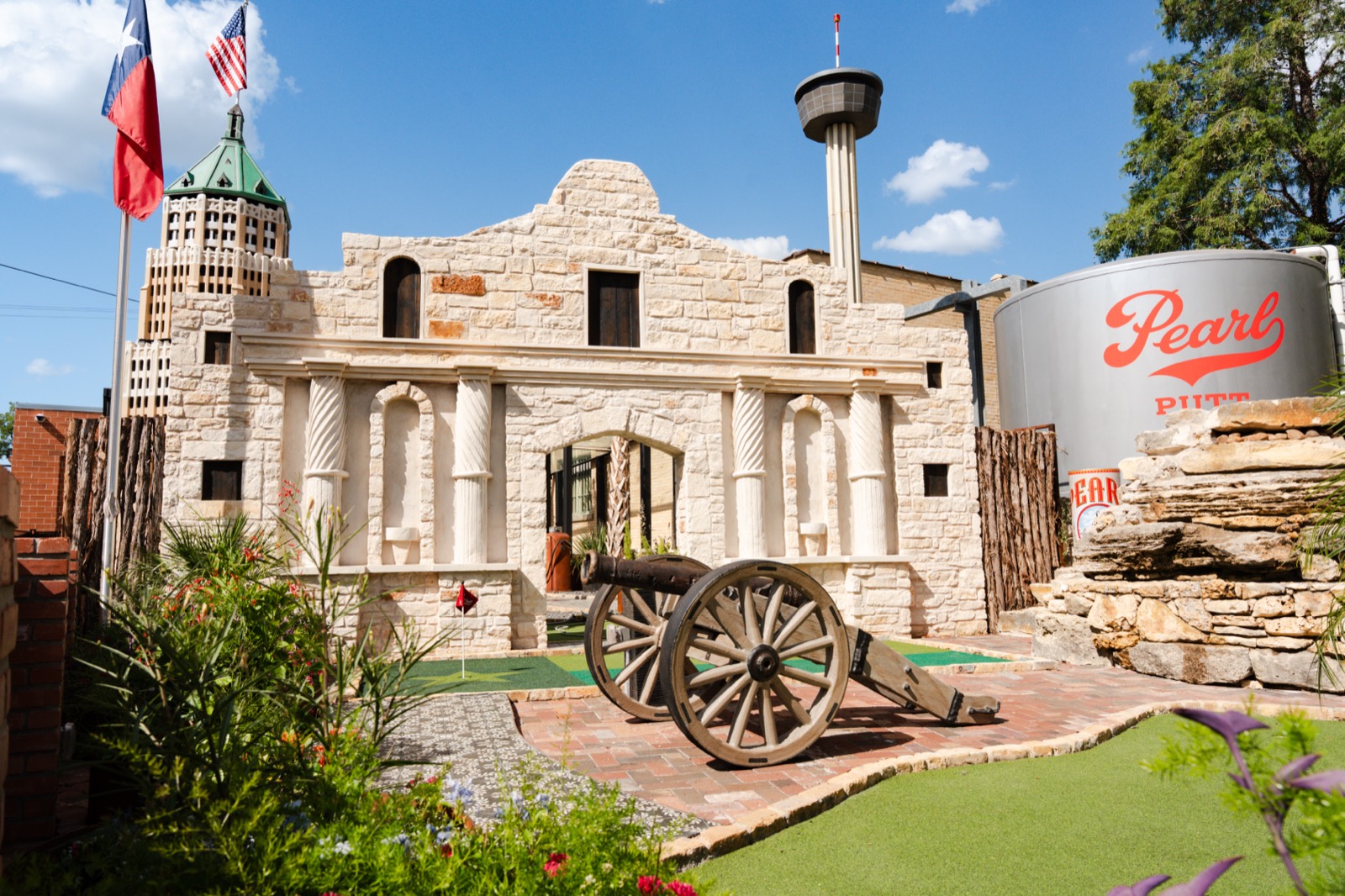 Alamo-style stone facade with an antique wagon beside the putting green