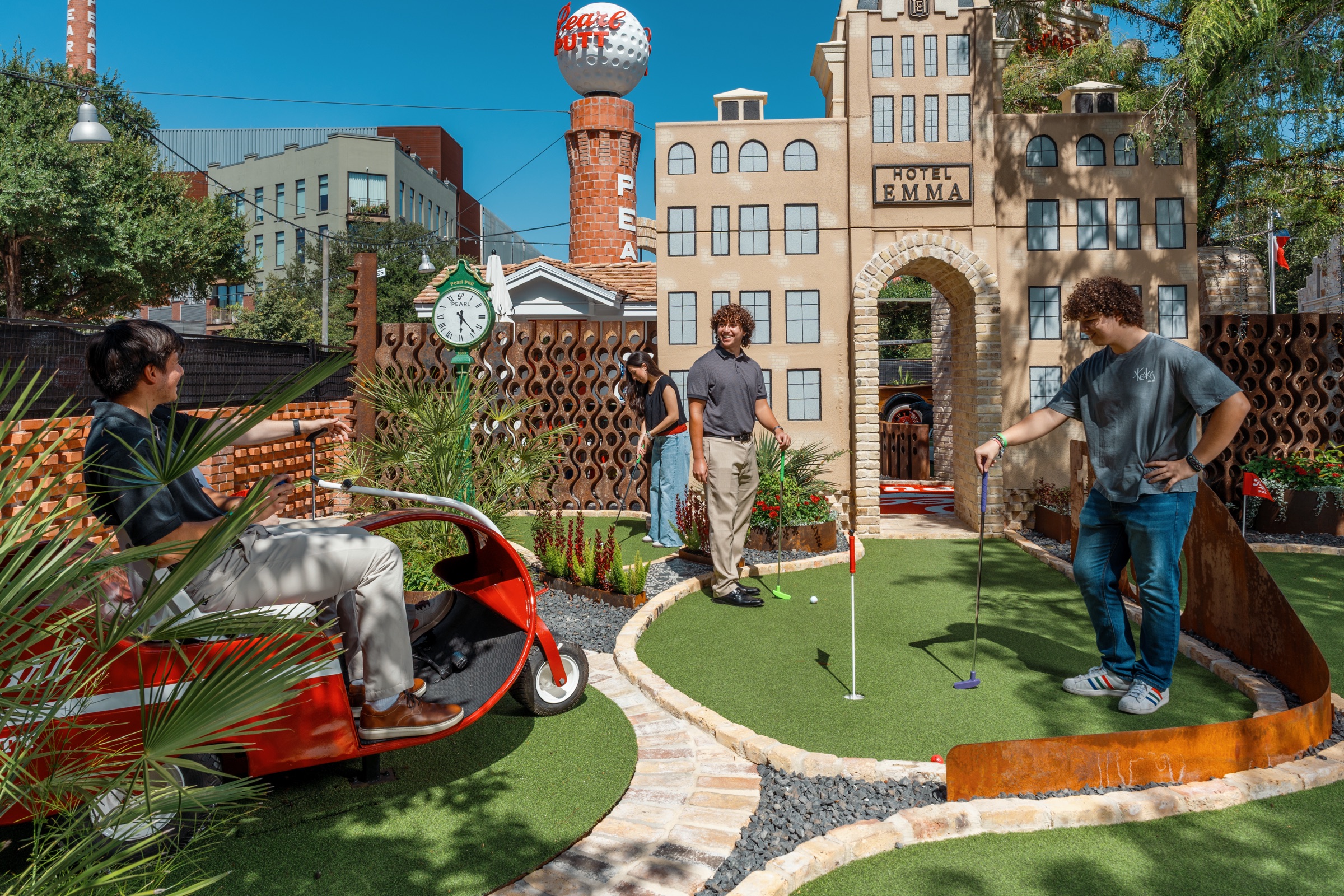 A group of friends taking their turns putting on the Pearl Putt course