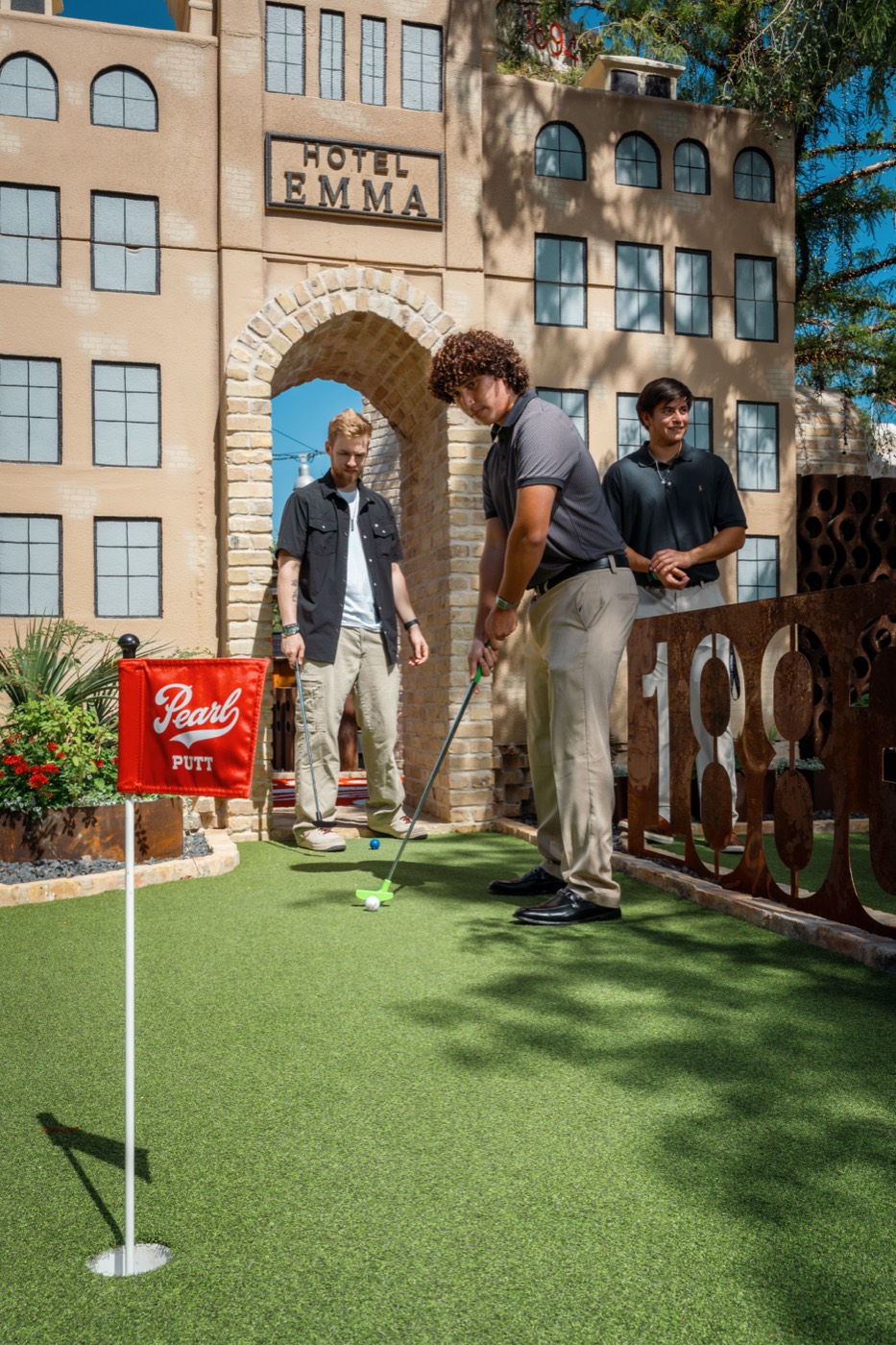 A group of friends taking their turns putting on the Pearl Putt course