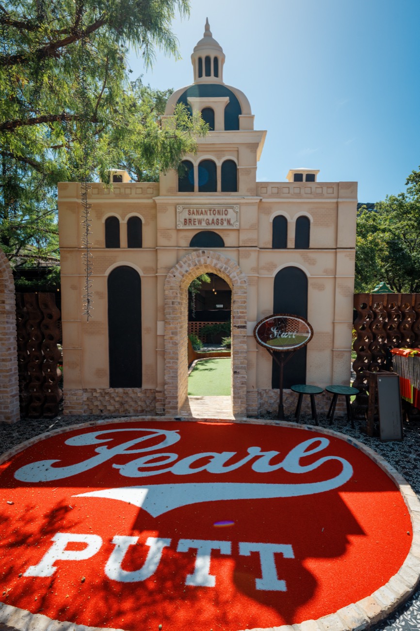Mission-style stone archway hole with the Pearl script logo on the green